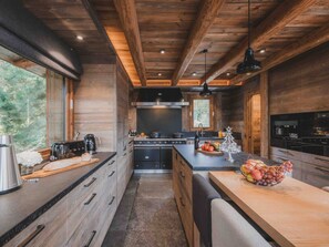 A modern kitchen with wooden cabinetry, a central island, and a large window. - Chalet with pool, pets welcome, Mont Blanc view - 11 guests (Les Houches)