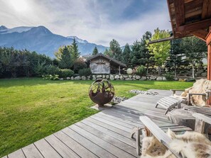 A wooden deck with a rustic cabin in the background, surrounded by a well-maintained lawn and a mountain view. - Chalet with pool, pets welcome, Mont Blanc view - 11 guests (Les Houches)