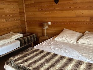 A wooden cabin room with two beds, a nightstand, and a lamp. - South view apartment, pets welcome - 4 guests (Valloire)