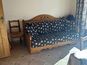 A wooden sofa with a patterned cover, a wooden chair, and a lamp in a room with tiled flooring. - Apartment pet-friendly - 5 guests (Valloire)
