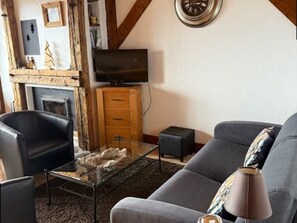 A living room with a fireplace, a television, a sofa, and a coffee table. - Apartment with balcony, mountain view - 6 guests (Les Saisies)