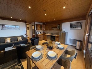 A compact living space with a dining area, kitchenette, and a sofa set. - Apartment with balcony, mountain view - 6 guests (Les Saisies)