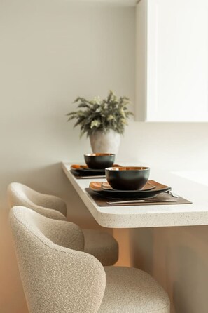A minimalist dining area with a long table, two black bowls, a potted plant, and a window. - Hop Inn Private Hot Tub Fire Pit Mtn Views (Waynesville)