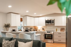 A modern kitchen with white cabinets, stainless steel appliances, and a central island. - Hop Inn Private Hot Tub Fire Pit Mtn Views (Waynesville)