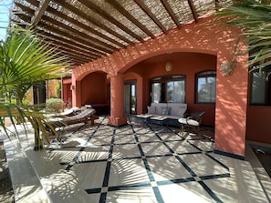 A covered outdoor seating area with a checkered floor, a sofa, and a table. - 2BR Apartment in West Golf, El Gouna (Red Sea Governorate)