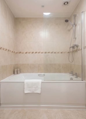 A bathroom with a bathtub, shower, and tiled walls. - Cosy 2-Bed | 3 Space Parking | M56 Nearby (Helsby)