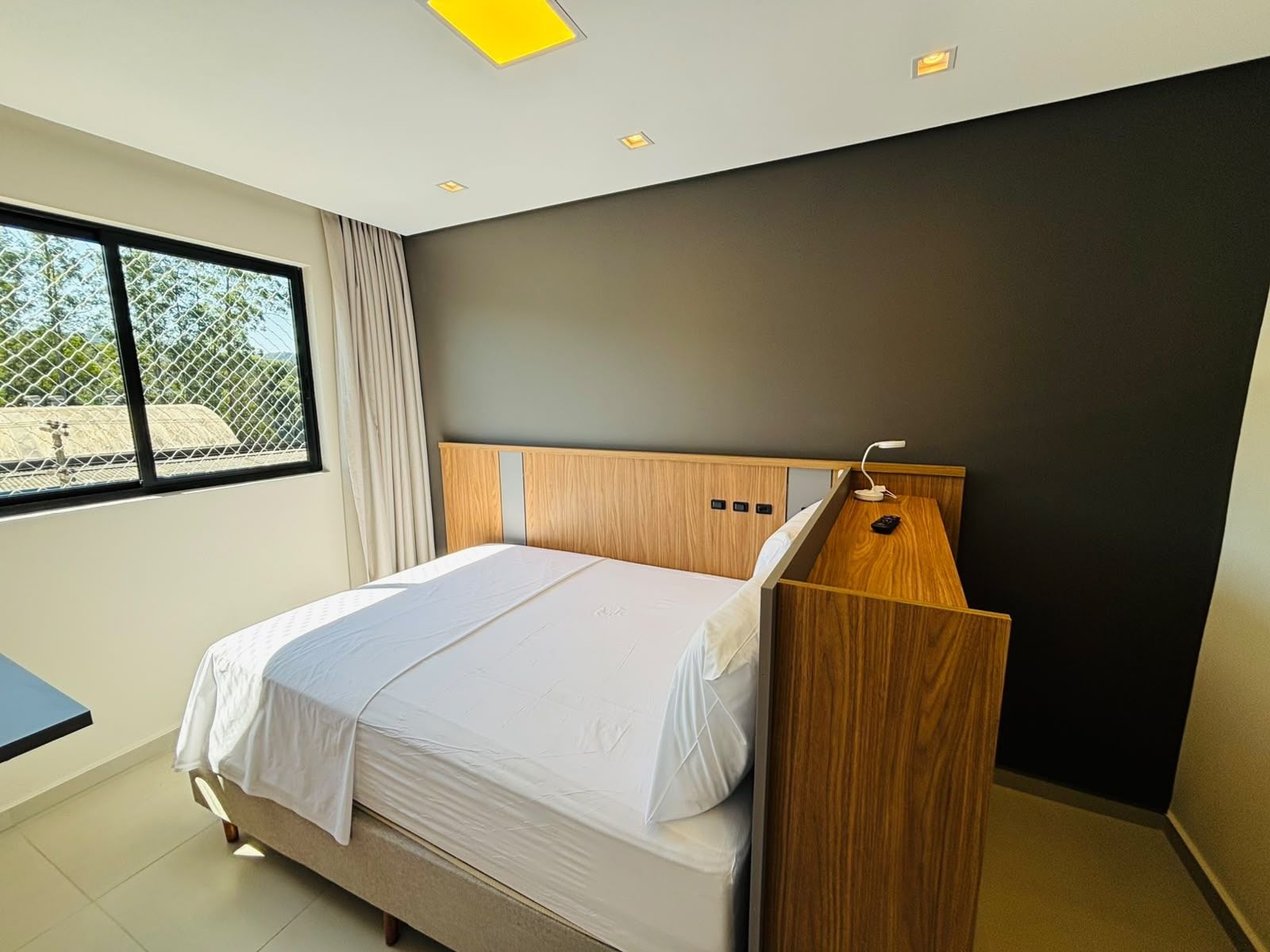 Un dormitorio moderno con cama, escritorio y ventana.
