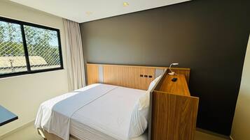 Un dormitorio moderno con cama, escritorio y ventana.