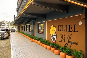 Un edificio con un letrero que dice 'ELIEL De Jaques' y una fila de macetas con plantas a lo largo de la acera.