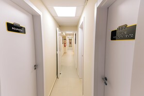 Un pasillo de hotel con puertas que indican 'ELIEL ROUPARIA' y 'ELIEL SALA DE MONITORAMENTO'.