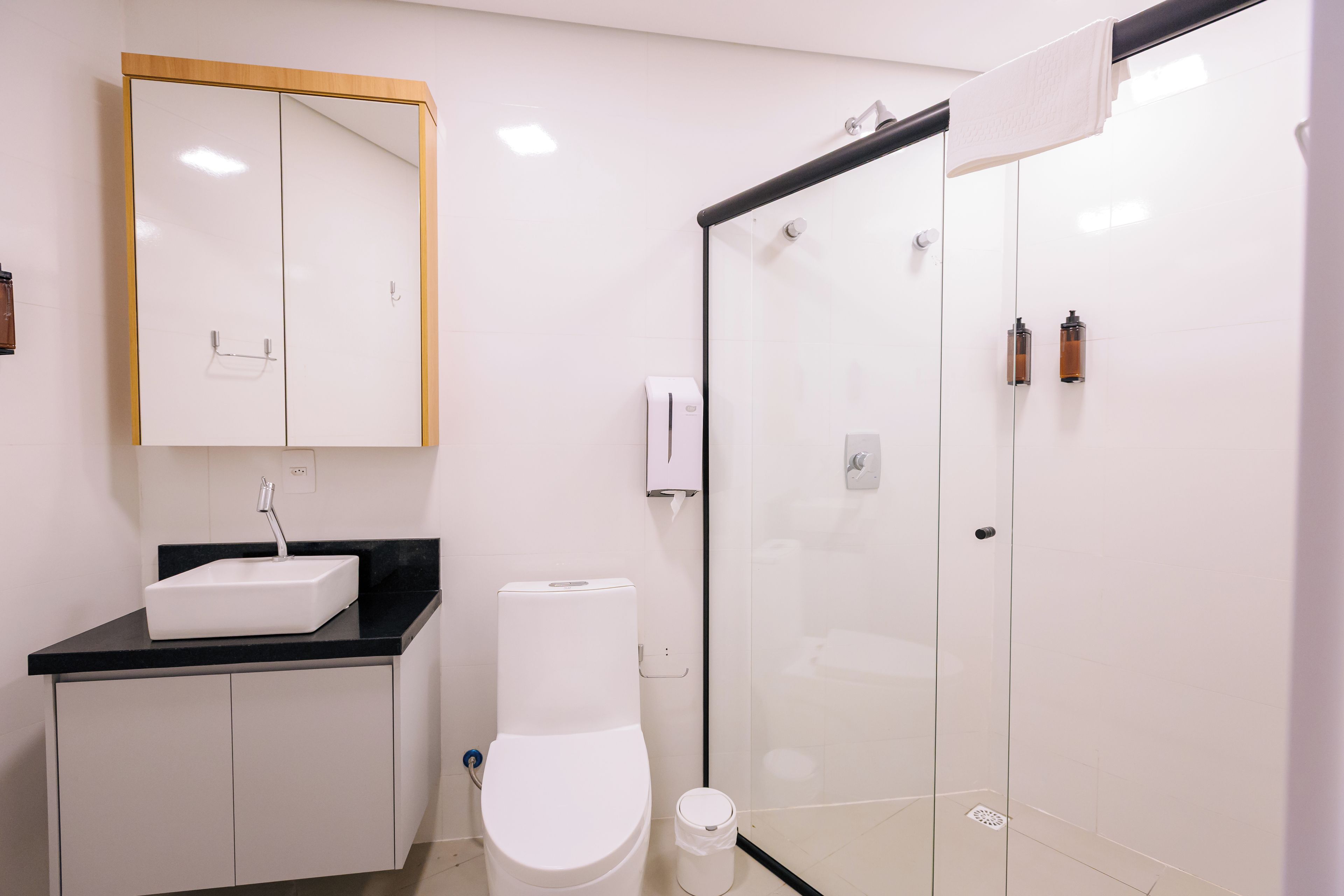 A modern bathroom with a white sink, mirror, toilet, and glass shower enclosure.