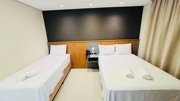Een hotelkamer met twee eenpersoonsbedden, een nachtkastje met een lamp en een neutraal kleurenpalet.