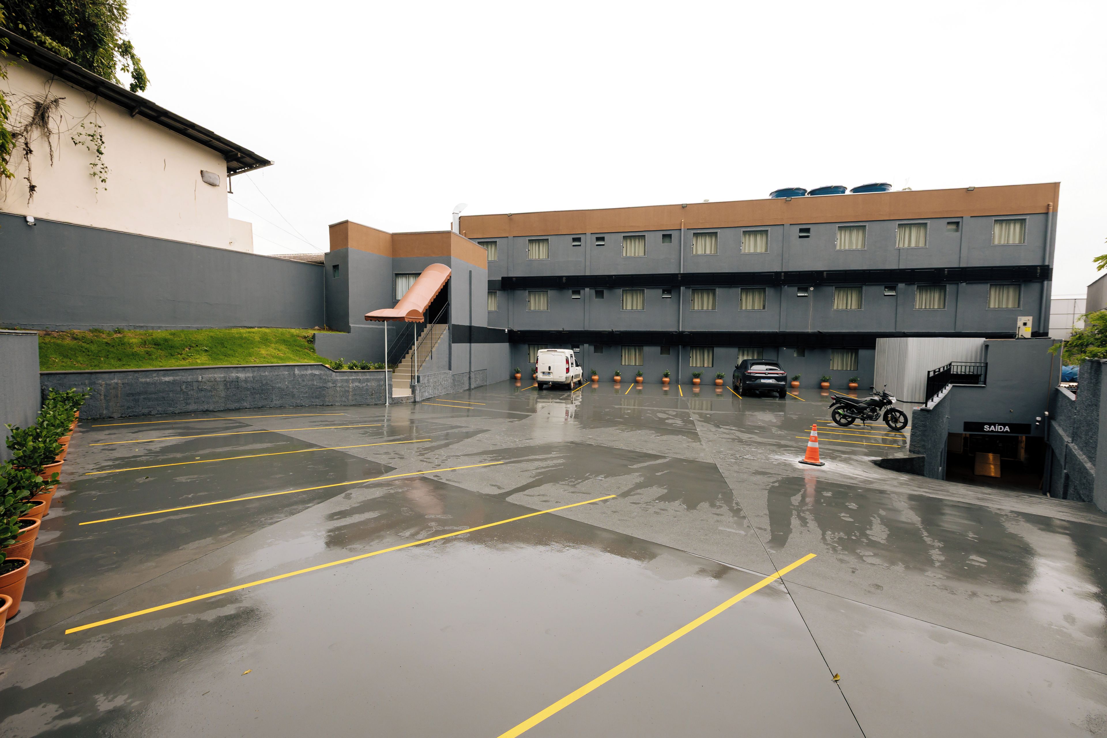 Een meerlaags parkeergarage met nat wegdek, aangeduide parkeerplaatsen en een trap naar een hoger niveau.