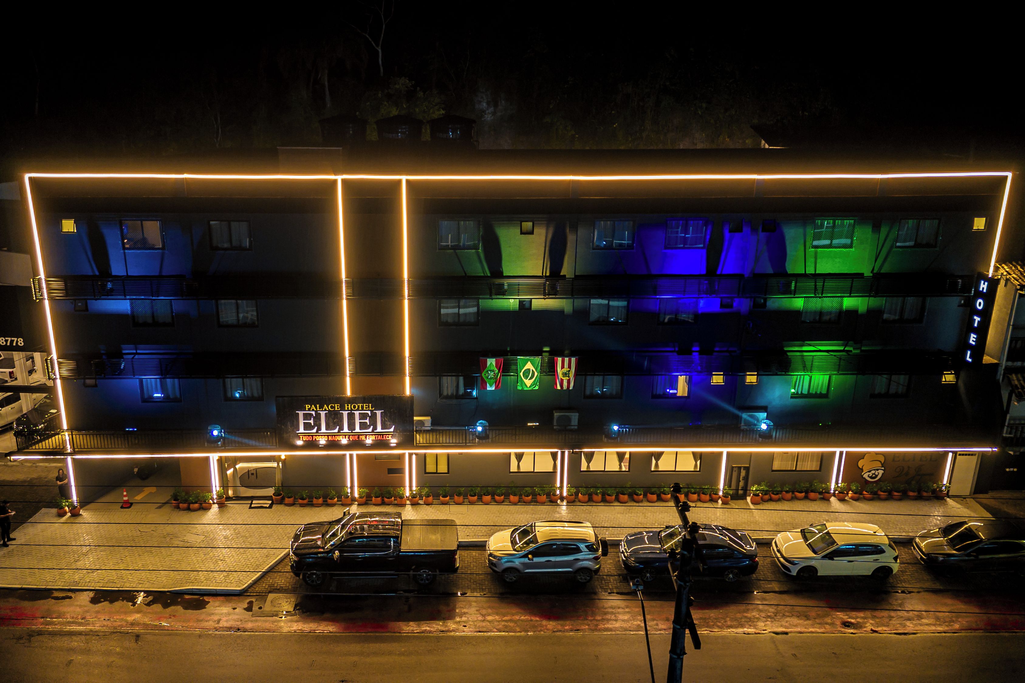Un hôtel reconnaissable à son enseigne bien visible, doté de plusieurs étages et disposant d’un parking où sont stationnées plusieurs voitures.