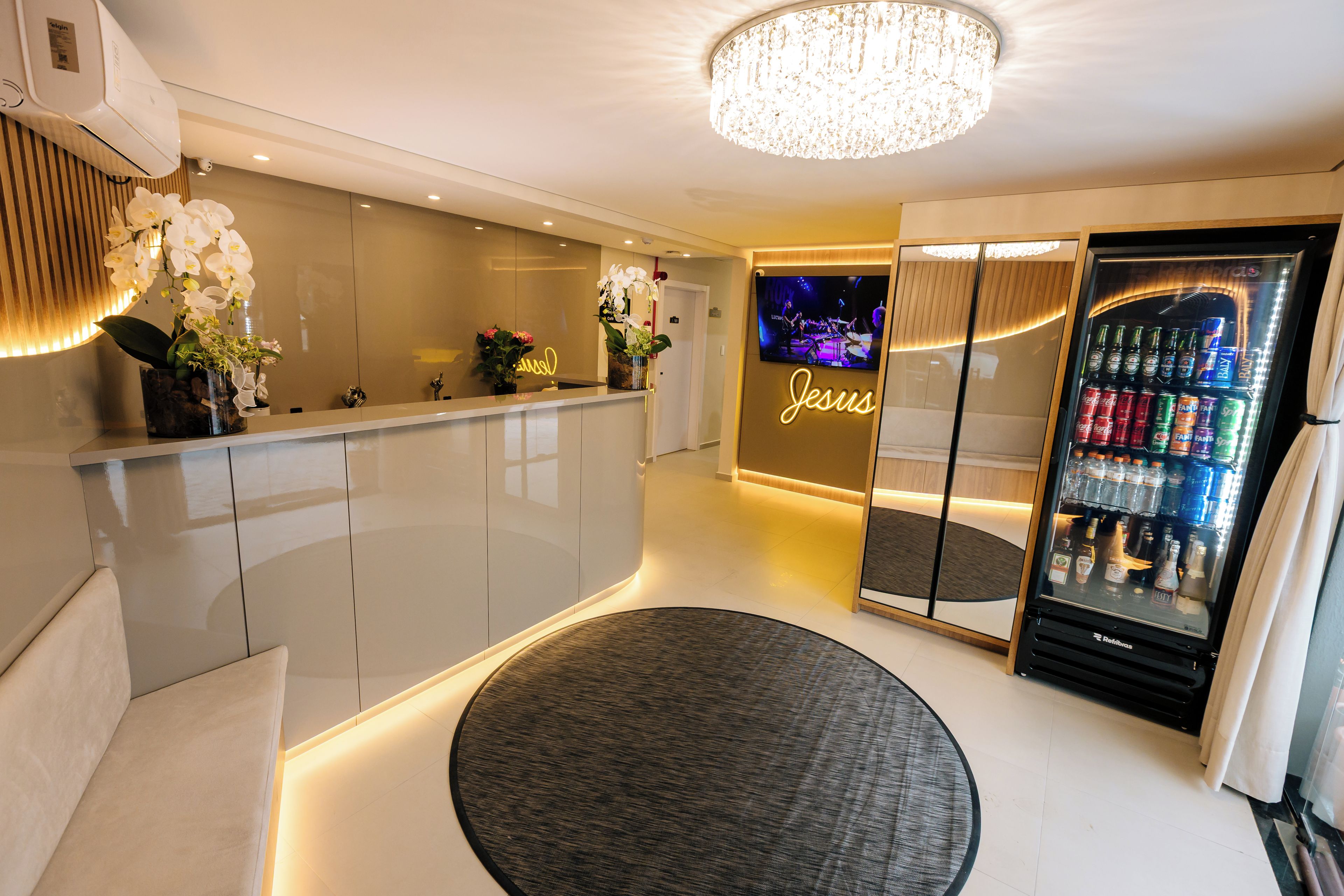 Una zona de recepción moderna con un letrero de neón, una pantalla de televisión y un minibars.