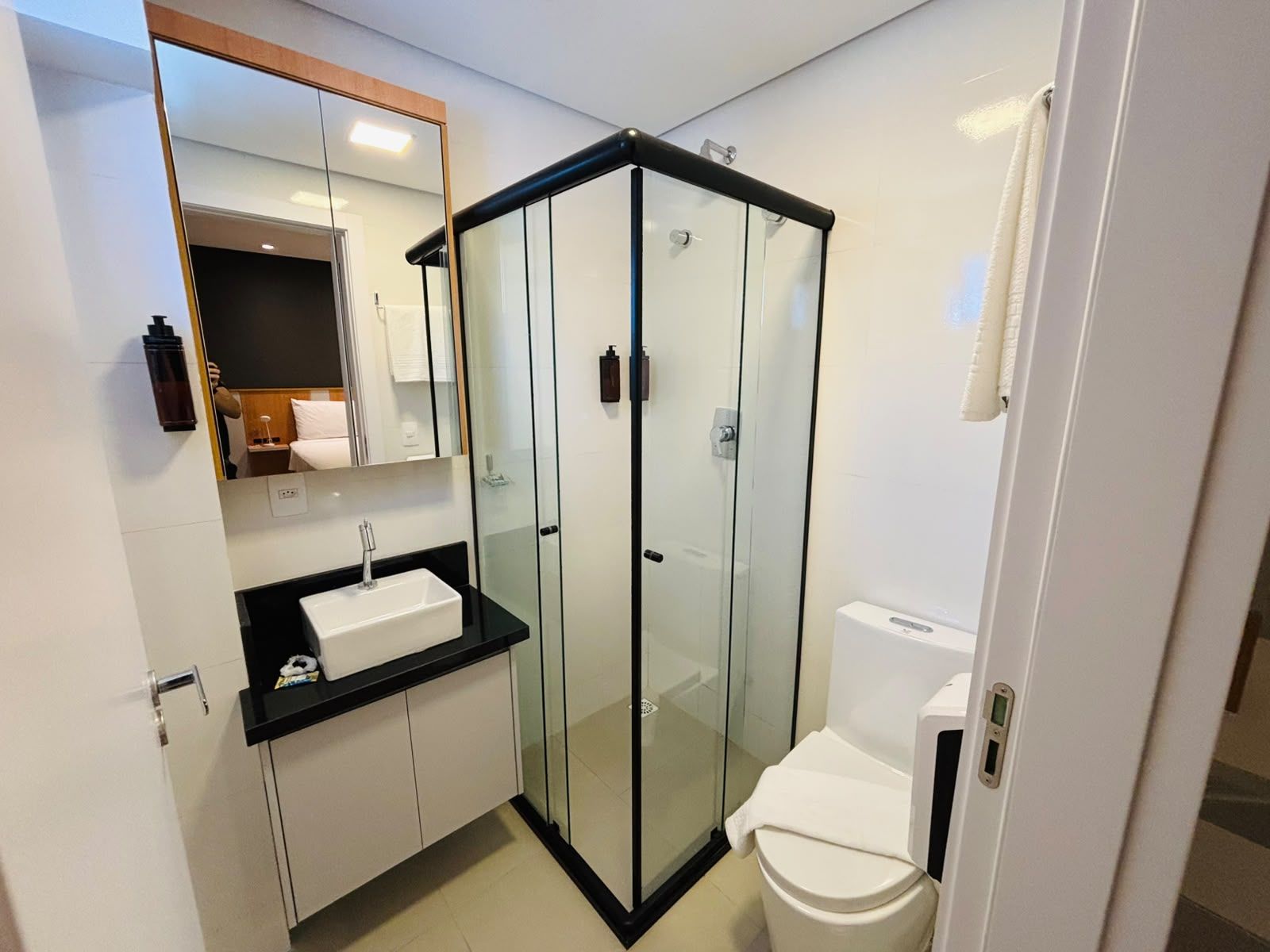 Ein modernes Badezimmer mit einer Duschkabine, einem weißen Waschbecken und einer Toilette.