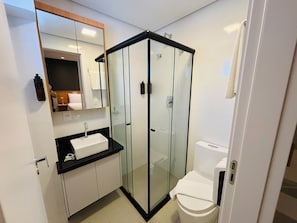 Un baño moderno con ducha envuelta en vidrio, un lavabo blanco y un inodoro.