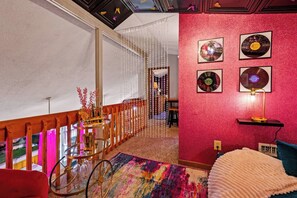 A room with a red textured wall, a ceiling with a skylight, and a staircase leading to another level. - Dolly Vibes|Private|Hot Tub|Karaoke|Beauty Room (Sevierville)