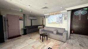 A lobby with a reception desk, a sofa, a small table, and a wall-mounted screen. - Noor Al Salam Hotel 1 (Makkah)