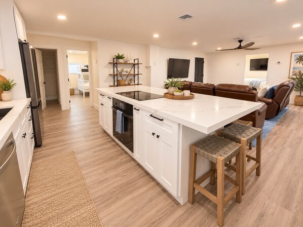 A modern kitchen with an island, built-in oven, and white cabinetry.