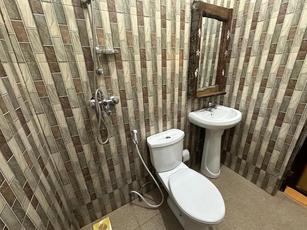 Un baño con pared de azulejos, inodoro, lavabo y ducha.
