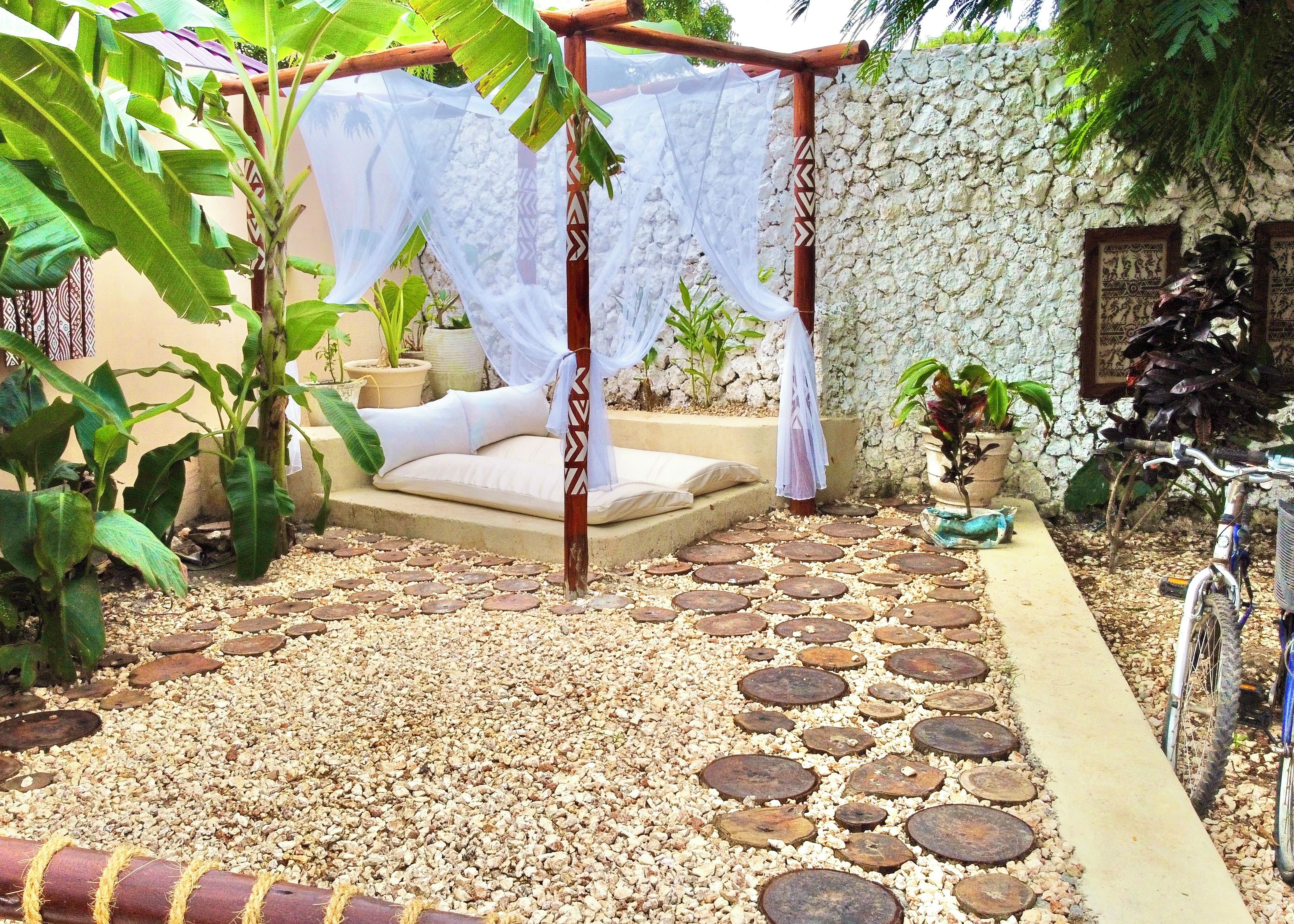 A garden with a bed, a canopy, and a stone wall.