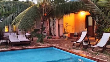 A pool area with lounge chairs, a small table, and a potted plant.
