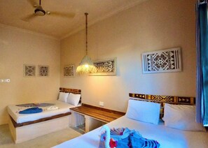 A hotel room with two beds, a ceiling fan, and decorative wall art. - Ocean Breeze Boutique Hotel (Nungwi)