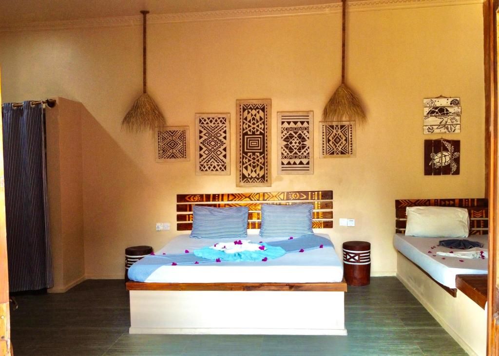Une chambre d’hôtel avec un grand lit, deux tables de chevet, une petite table et un rideau.