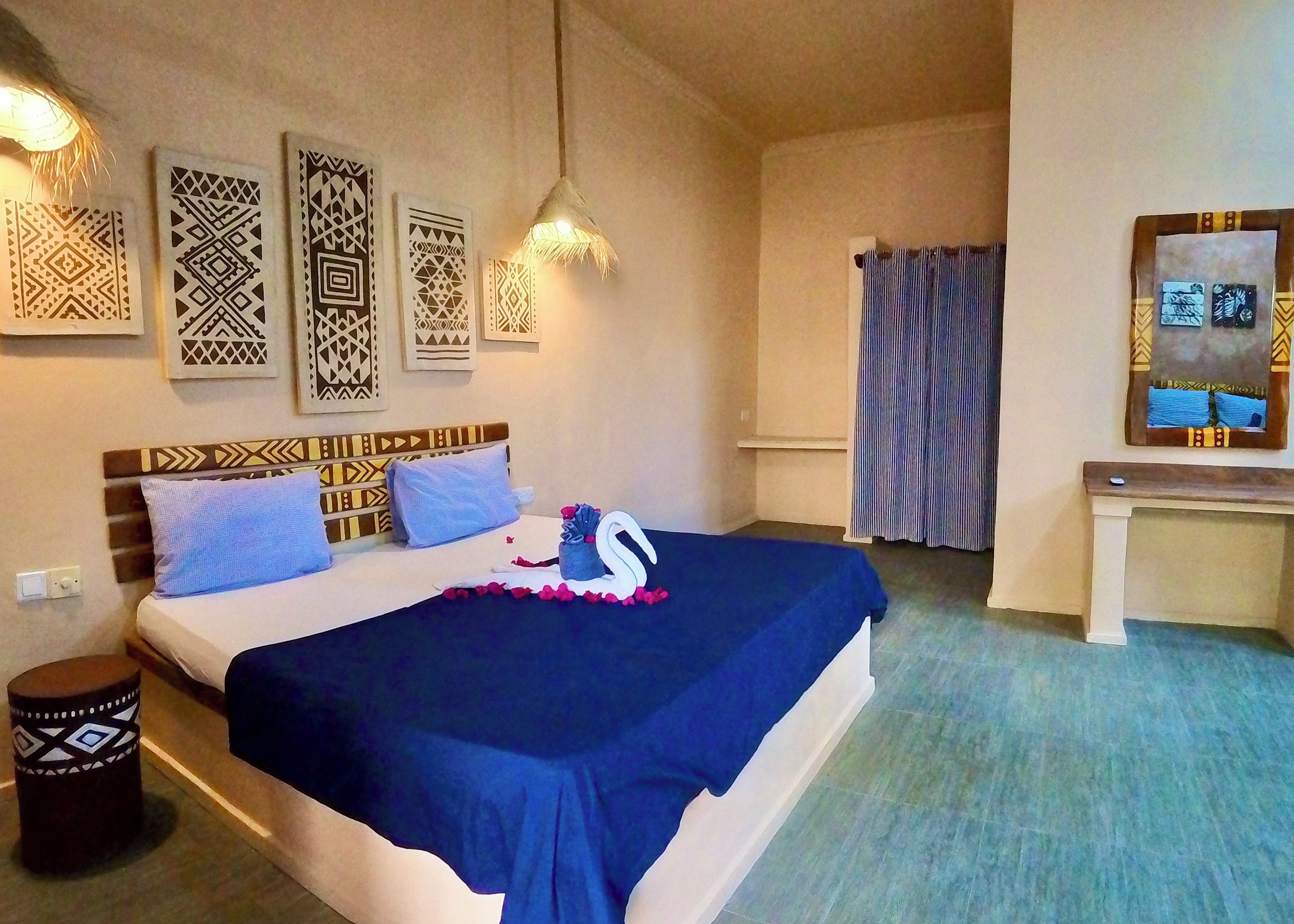 Une chambre d’hôtel comprenant un lit, une table de chevet, un miroir et des œuvres d’art décoratives au mur.