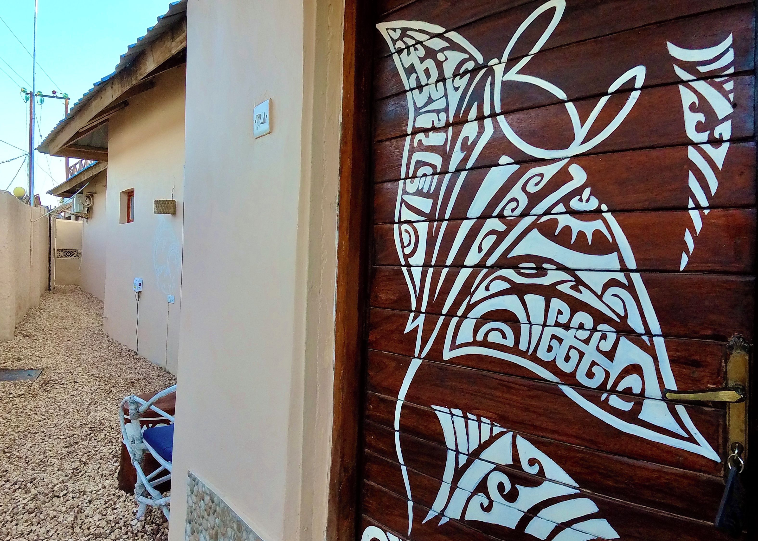 Una puerta de madera con elaborados adornos blancos, una pared color beige y una reja de metal.
