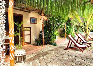 A tropical outdoor area with a pathway, lounge chairs, and potted plants. - Ocean Breeze Boutique Hotel (Nungwi)
