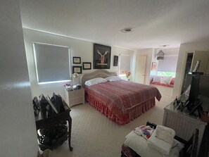 A bedroom with a bed, bedside table, dresser, and a window with blinds. - The Scotch Bonnett Beach House - Best Location! (Nags Head)