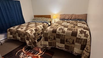 Ein Schlafzimmer mit zwei Betten, einem Nachttisch, einer Lampe und einem Teppich mit einem Hirschmuster.