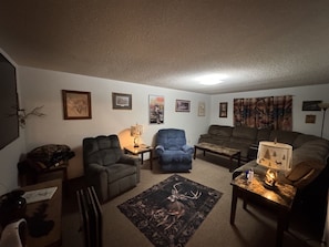 A living room with a sofa, armchairs, a coffee table, and a rug.