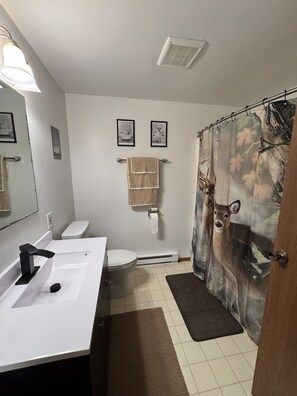 A bathroom with a white sink, toilet, and shower curtain with a deer print.