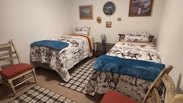 Makuuhuoneessa on kaksi sänkyä, ruutukuviollinen matto ja tuoli.