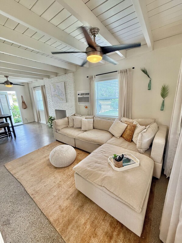 A modern living room with a sectional sofa, a round pouf, and a coffee table with a tray.