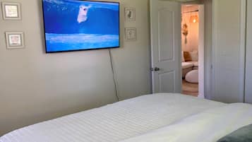 Un dormitorio con cama, televisión montada en la pared y ventilador de techo.