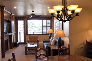 A cozy living room with a fireplace, a sofa, a coffee table, and a dining table. - Grand Lodge Peak 7 - 2 BR Condo at Independence Lift. Dec. 12th to Dec. 19th (Breckenridge)