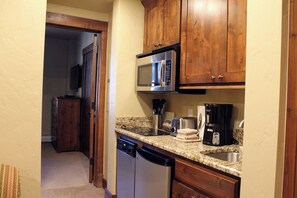 A compact kitchen with wooden cabinets, a microwave, a coffee maker, and a dishwasher. - Grand Lodge Peak 7 - 2 BR Condo at Independence Lift. Dec. 12th to Dec. 19th (Breckenridge)