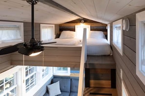 Ein Schlafzimmer im Loft-Stil mit Bett, Pendelleuchte und Blick ins Freie.