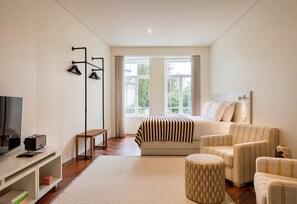 A modern hotel room with a bed, a sofa, a TV, and a desk. - Premium Studio Suite - Vila Catarina Luxury Apartments (Porto)