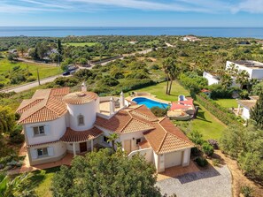 A multi-story house with a swimming pool, surrounded by lush greenery and a view of the sea. - Casa Carpe Diem - 5 Bed Villa With Panoramic Sea Views & Private Pool (Carvoeiro)