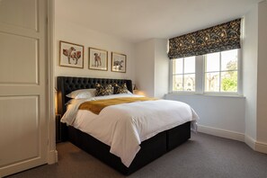 Une chambre à coucher avec un lit, une fenêtre donnant sur un beau paysage et trois tableaux encadrés accrochés au mur.