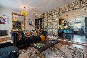 Ein modernes Wohnzimmer mit einer schwarzen Couch, einem Couchtisch und einer Wand mit Muster.