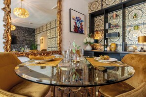 A dining area with a round glass table, gold chairs, and a decorative mirror. - Luxury Loft Above The Chipping Steps, Tetbury  (Tetbury)
