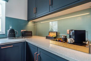 Eine moderne Küche mit dunklen Schränken, einer Arbeitsplatte und diversen Geräten, darunter eine Kaffeemaschine und ein Toaster.
