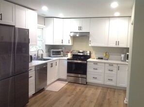 A modern kitchen with white cabinets, stainless steel appliances, and a wooden floor. - Your Peaceful Durham Getaway – Near Duke, UNC & RTP (Durham)
