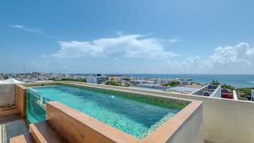 A rooftop swimming pool with a view of the ocean and cityscape.